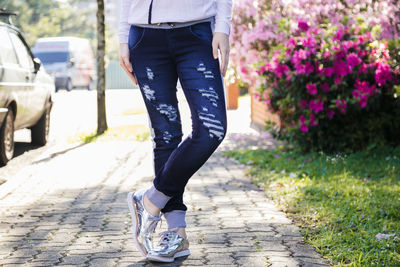 Low section of woman wearing shoes while standing footpath