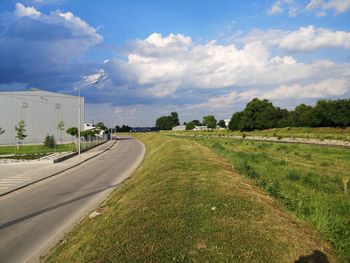 Road amidst field against sky