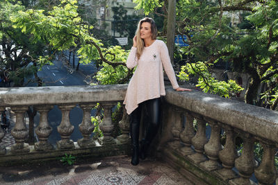 Woman looking away while standing by retaining wall