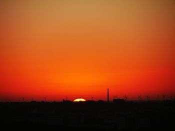 Silhouette buildings against orange sky