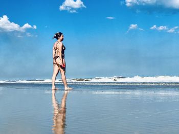 Woman standing on beach against sky