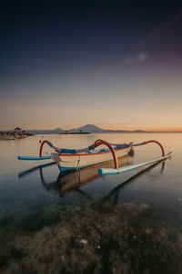 Deck chairs on beach against sky during sunset