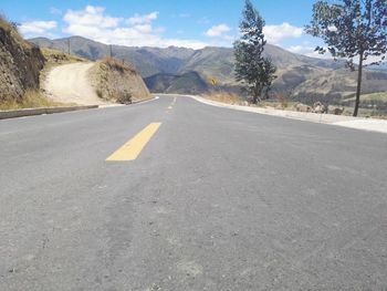 Empty road by mountains against sky