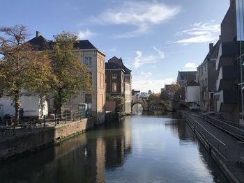 Buildings by river against sky in city