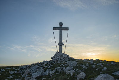 Low angle view of cross tower against sky during sunset