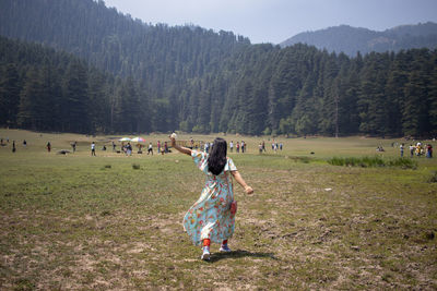 A back facing indian woman walking freely and happily in a valley of hills