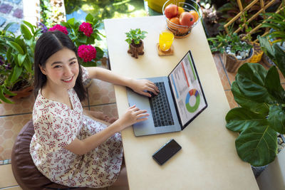 High angle view of woman using phone on table