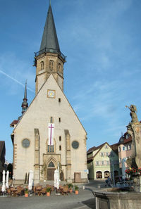 Clock tower amidst buildings in city against sky