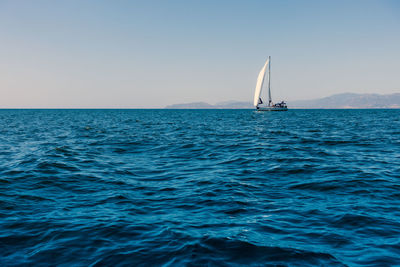 Sailboat sailing in sea against clear sky