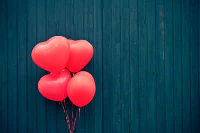 Pink heart shape balloons against blue wooden wall