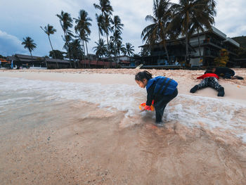 Sibling playing sand at the beach together.