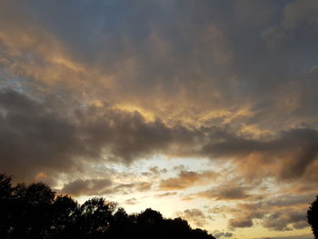 Low angle view of silhouette trees against dramatic sky