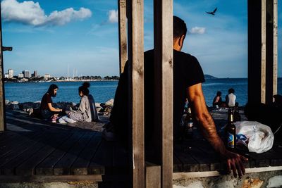 People sitting by sea against sky