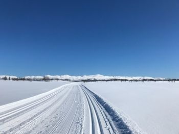 Snow covered landscape against clear blue sky