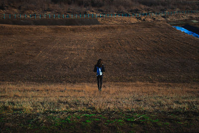 Rear view of woman walking on field