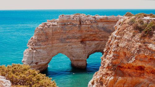 Rock formation by sea against clear blue sky