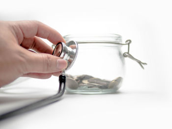 Close-up of hand holding glass over white background