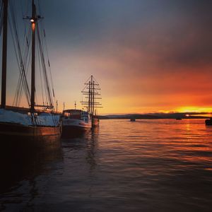 Sailboats in sea against sky during sunset