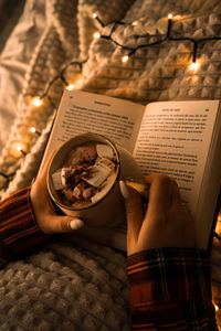 Christmas decorations with lights, hot drink, fruits and a good book