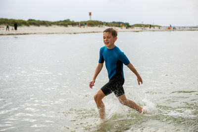 Full length of playful boy playing in sea