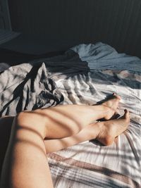 Low section of woman lying on bed