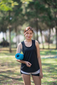 Portrait of a smiling young woman standing on field