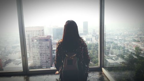 Rear view of woman looking through window