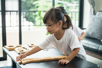 Woman looking through window while sitting on table