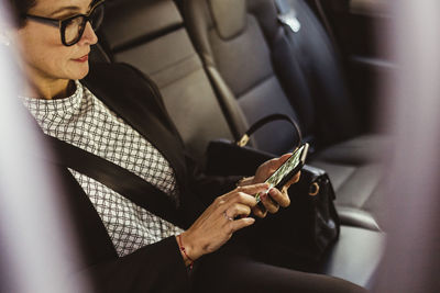 Female entrepreneur using device screen while sitting in car