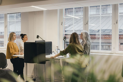 Female creative professionals planning over windmill in meeting at office
