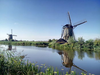 Traditional windmill by lake against sky