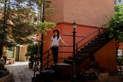 Woman standing by staircase against building