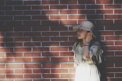 Woman standing against brick wall