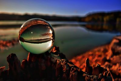 Close-up of crystal ball on rock against sky