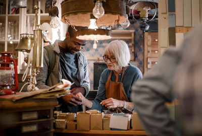 Senior female sales clerk assisting male customer with nails at hardware store