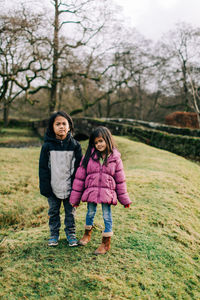 Full length portrait of mother and daughter against trees