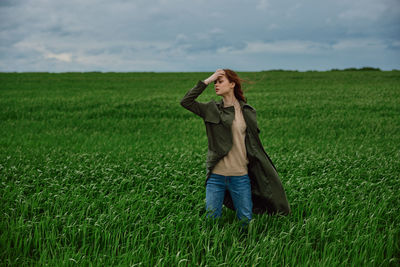 Portrait of young woman using mobile phone while standing on field