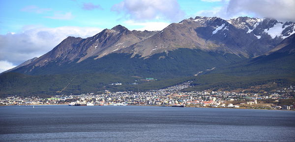 Scenic view of townscape by mountains against sky