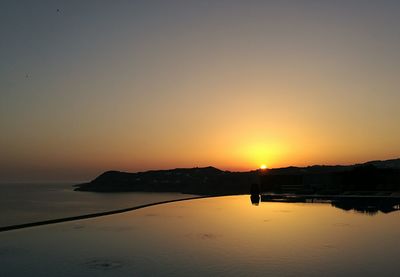 Scenic view of calm sea against orange sky