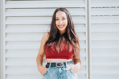 Portrait of young woman standing against wall