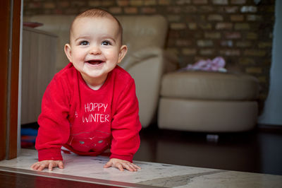 Cute baby girl kneeling at doorway