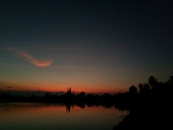 Silhouette trees by lake against sky during sunset