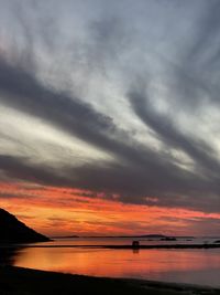 Scenic view of sea against dramatic sky during sunset