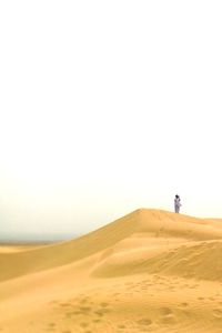 Man standing in desert against clear sky