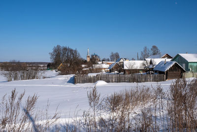 Houses on snow covered landscape against sky