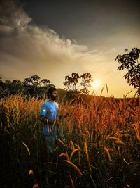 Rear view of man on field against sky during sunset