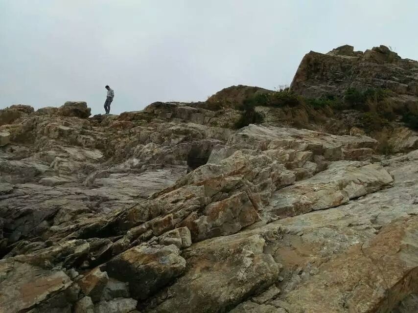 rock - object, rock formation, real people, nature, one person, outdoors, day, cliff, landscape, leisure activity, tranquility, mountain, sky, scenics, tranquil scene, hiking, beauty in nature, standing, full length, physical geography, adventure, lifestyles, low angle view, men, people