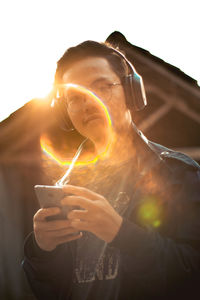 Portrait of man holding camera while standing outdoors