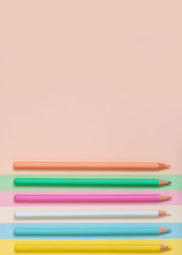 High angle view of colored pencils on pink background