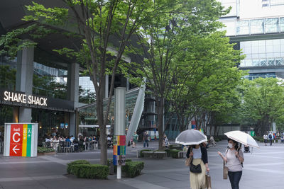 People walking on street amidst trees in city